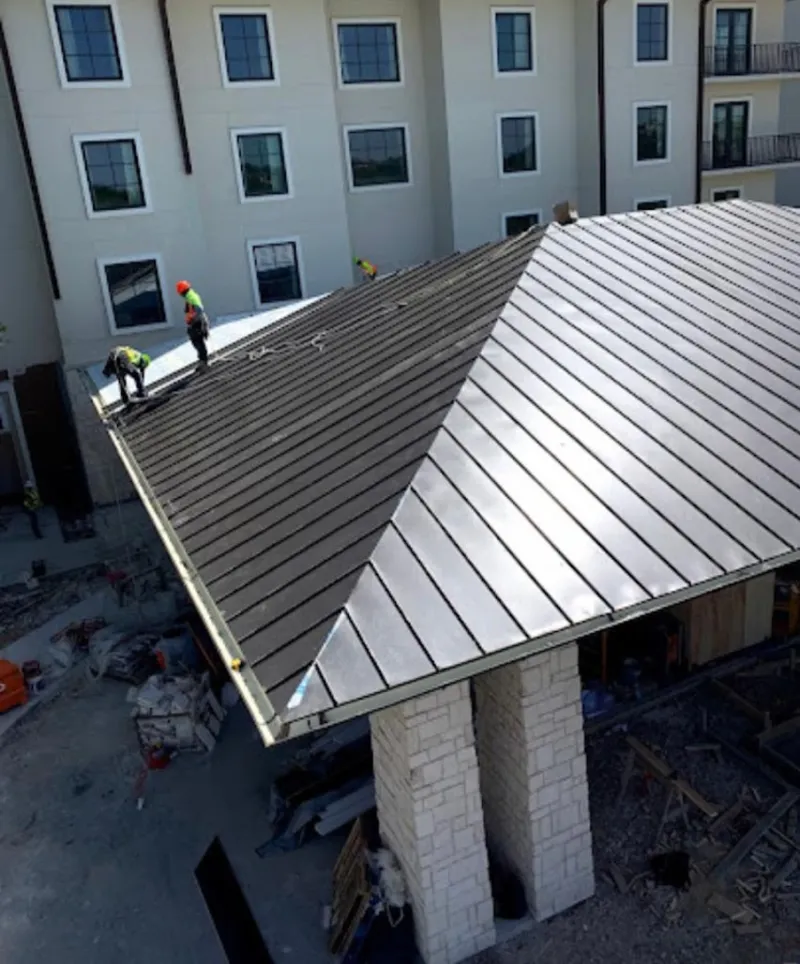 Crew installing standing seam metal roof panels on a commercial project in Southfield